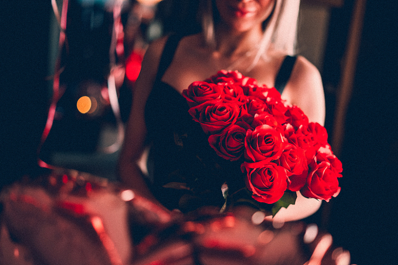 约会手持红玫瑰花束年轻女子