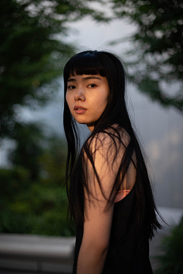 一个长着黑色长发的女人站在一棵树前