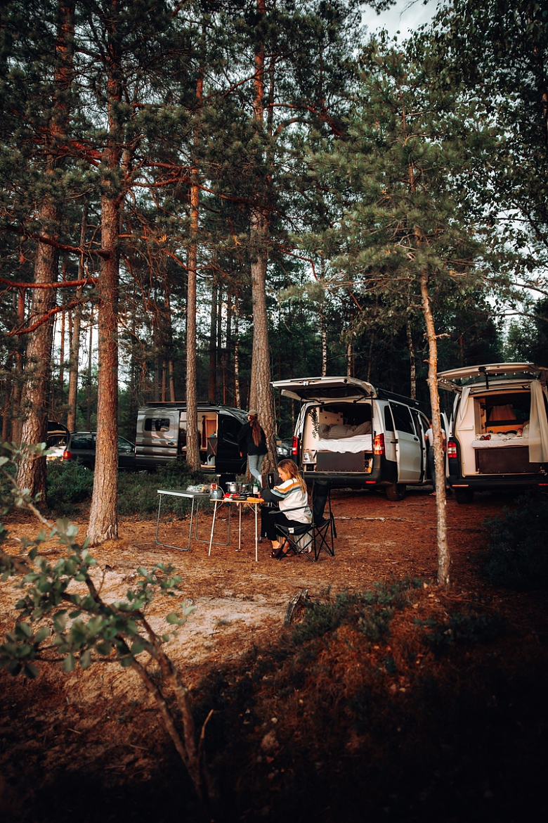 一群人围着树林里的露营车坐着