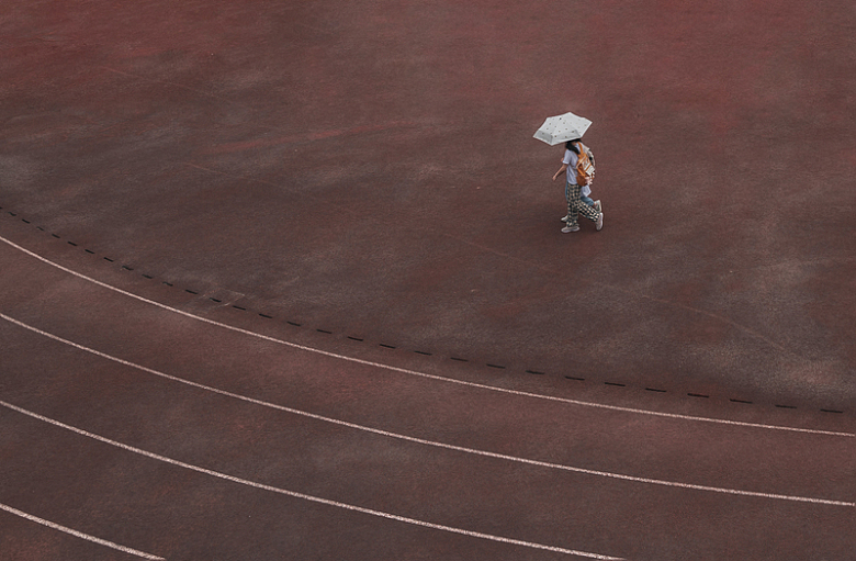 两个撑着伞在跑道上行走的人