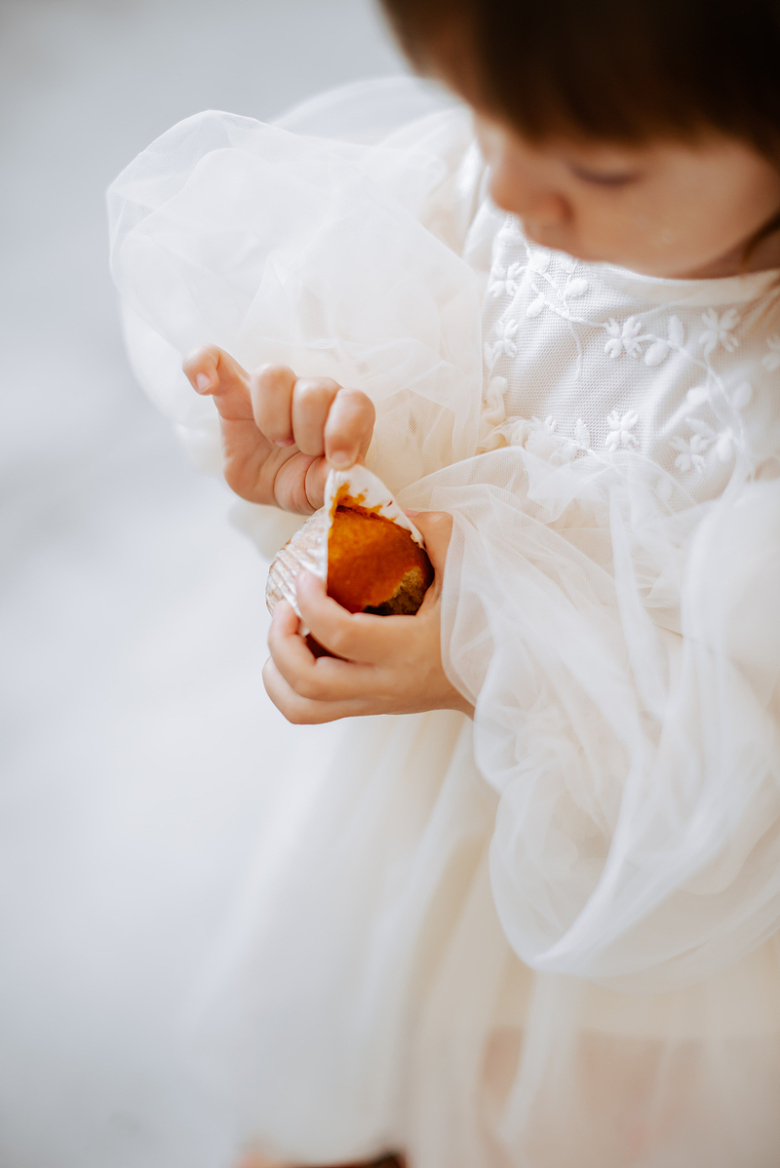 一个穿着白色连衣裙的小女孩拿着一块食物