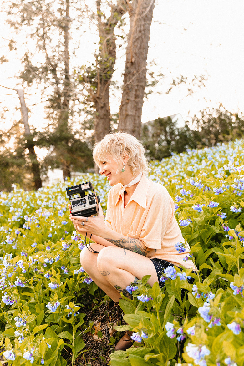 一个女人坐在花丛里手里拿着相机