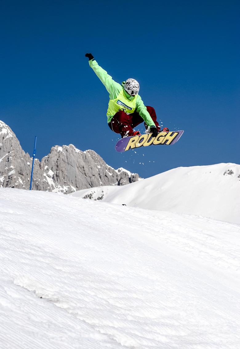 一名身穿绿色夹克的男子在白雪皑皑的山上滑雪