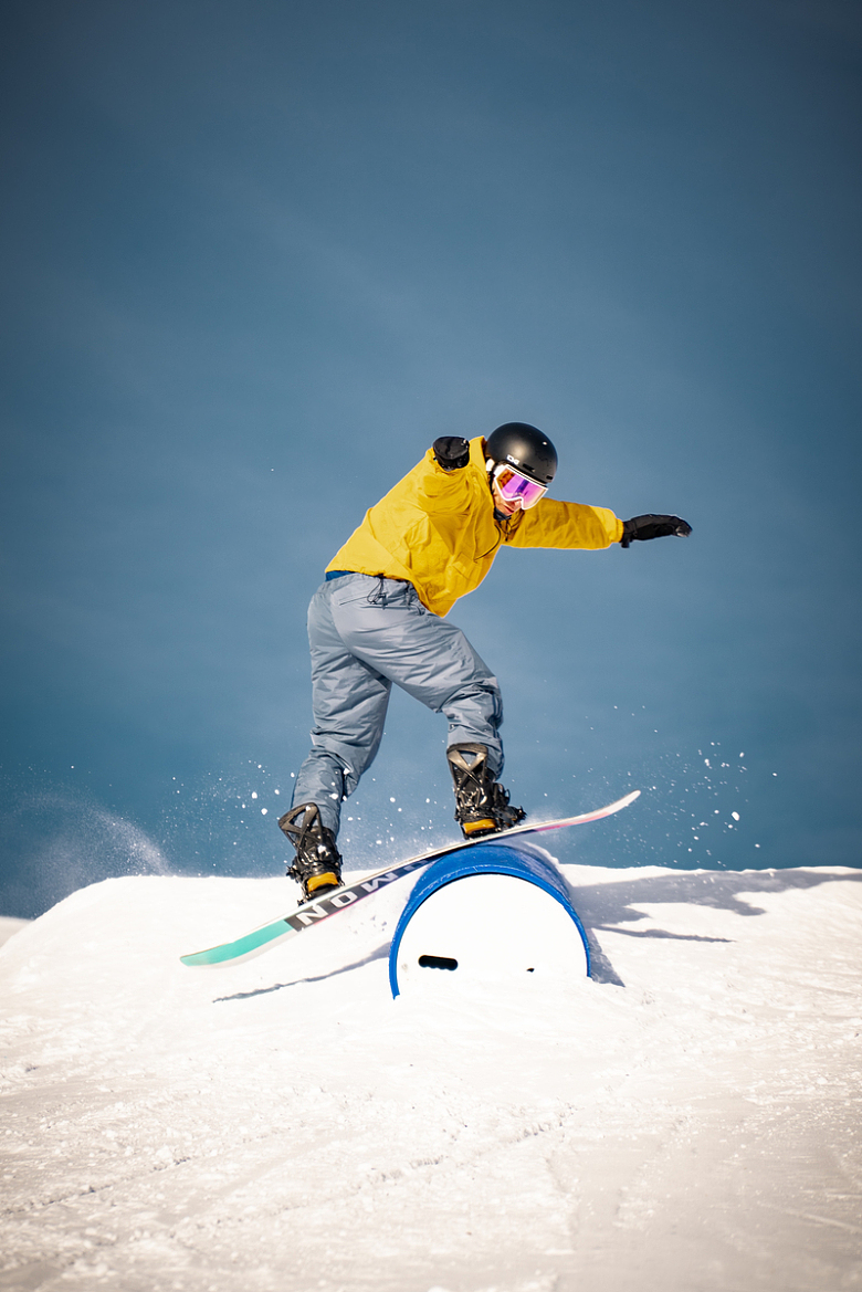 一名身穿黄色夹克和灰色裤子的男子在蓝色滑雪板上骑行