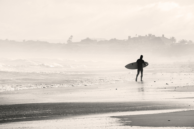 一个拿着冲浪板在沙滩上行走的人的侧影