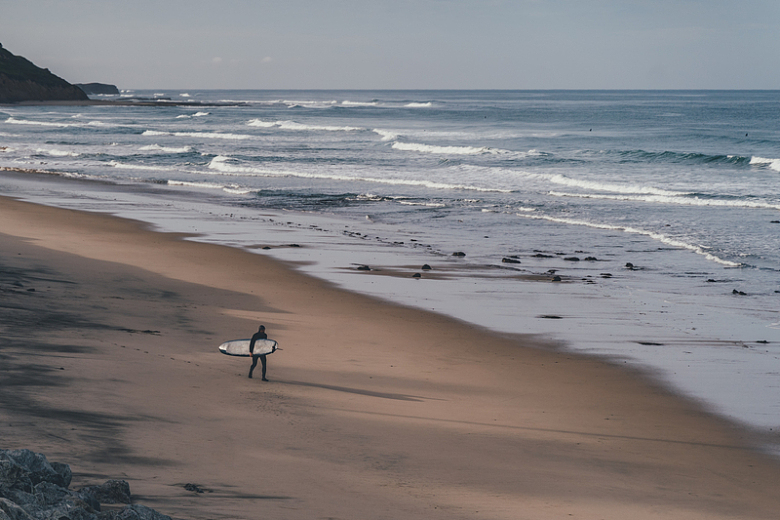 一名男子手持冲浪板在岸边行走
