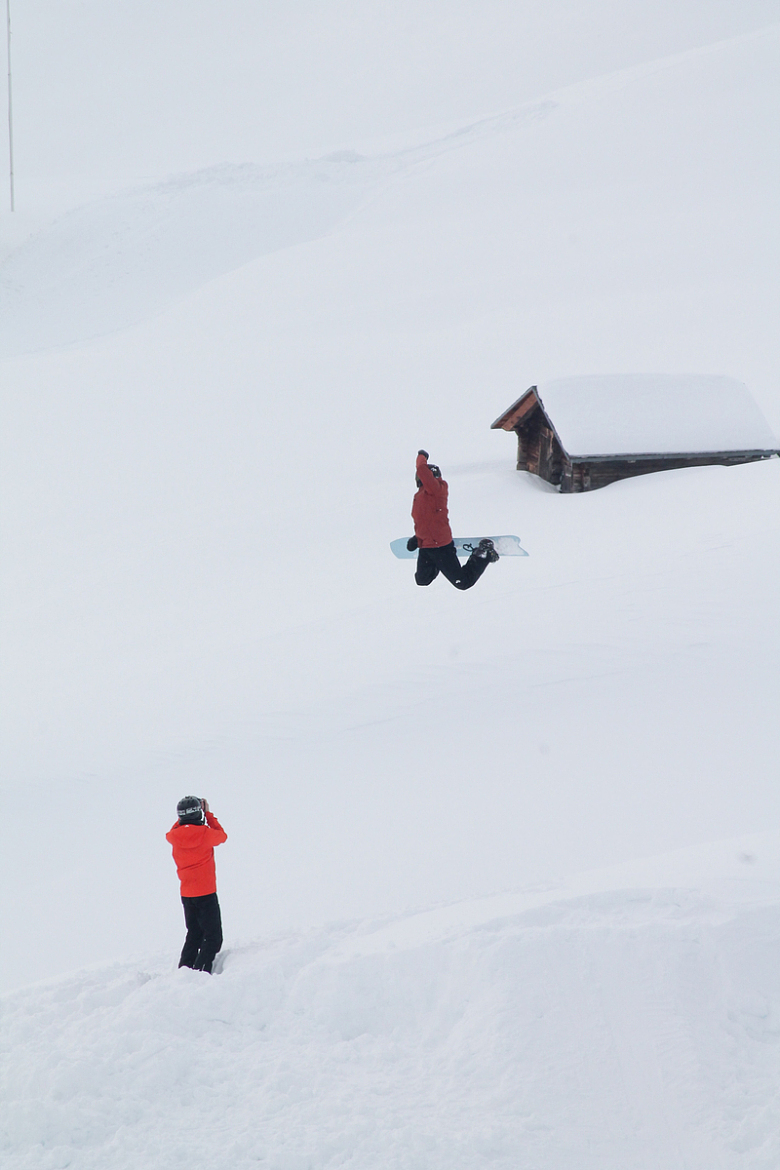 穿着红色夹克和黑色裤子的人在雪地上行走