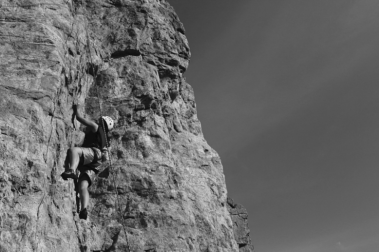 男子攀岩的灰度摄影