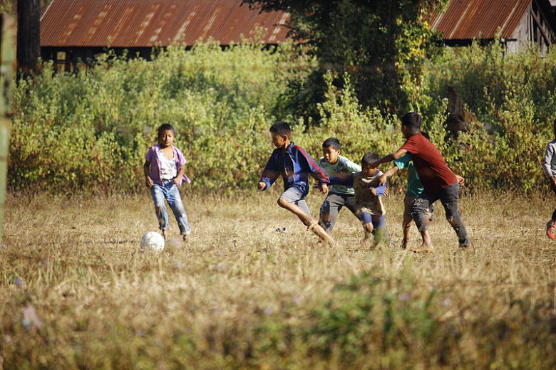 白天一群人在绿草地上踢足球