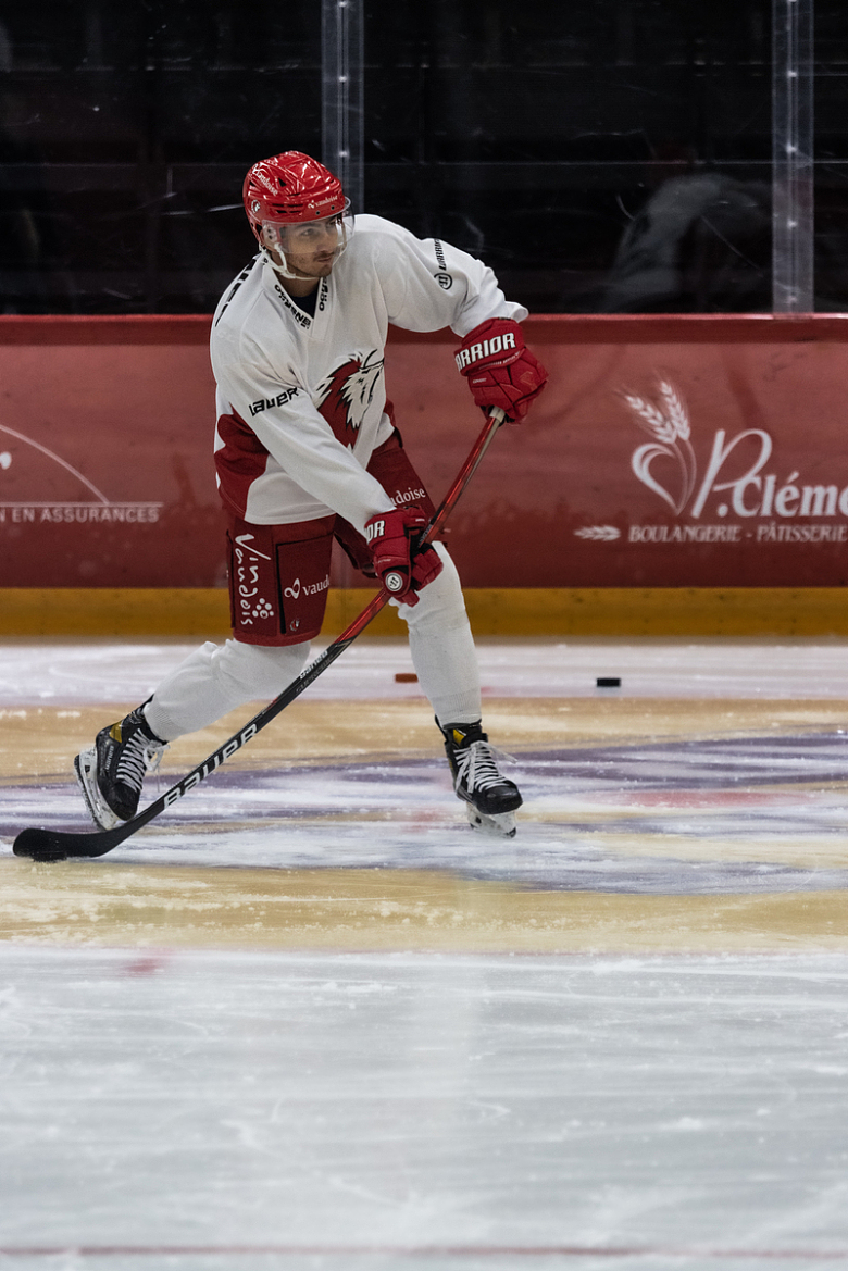 一个穿着白色和红色制服的男子在玩冰球
