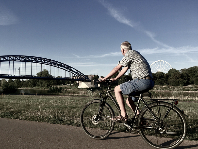 一名身穿灰白色条纹衬衫的男子白天在路上骑黑色自行车