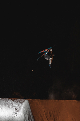 身穿蓝白衬衫和蓝色牛仔牛仔裤的男子站在黑色表面