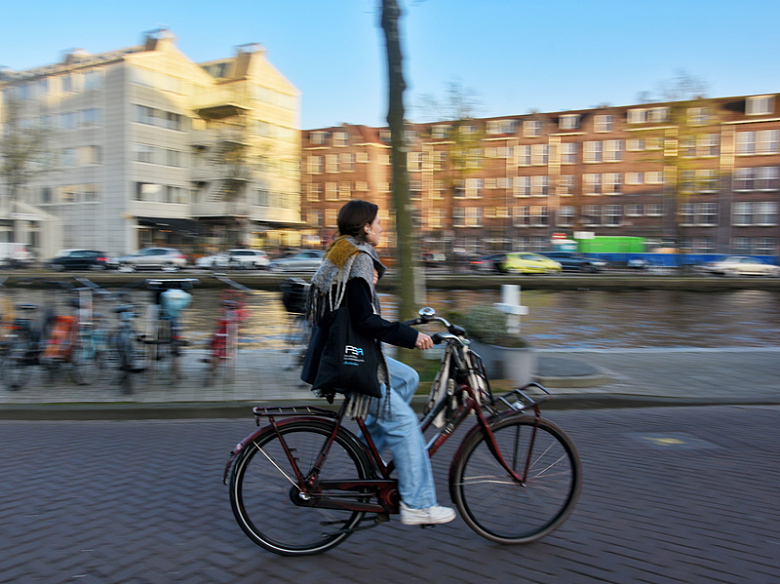 一个女人骑着自行车在河边的街道上行驶