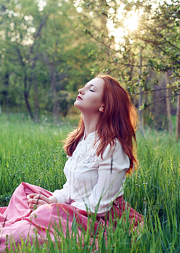 坐在绿色草地上冥思遐想的美女