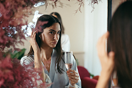 女人拿着香槟酒照镜子