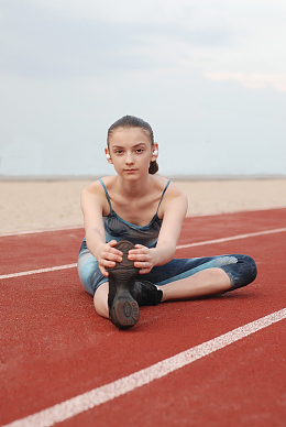在田径场上压腿的少女美女