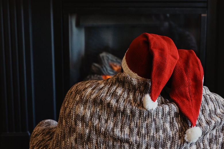 一对戴着圣诞老人帽的夫妇坐在壁炉旁