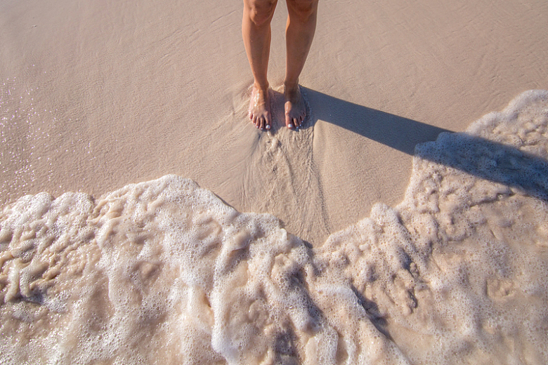 双脚站在沙滩浪花上