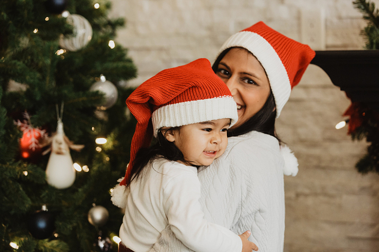 戴着圣诞老人帽蹒跚学步的孩子和妈妈