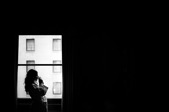 窗口的女人拿着早晨的咖啡