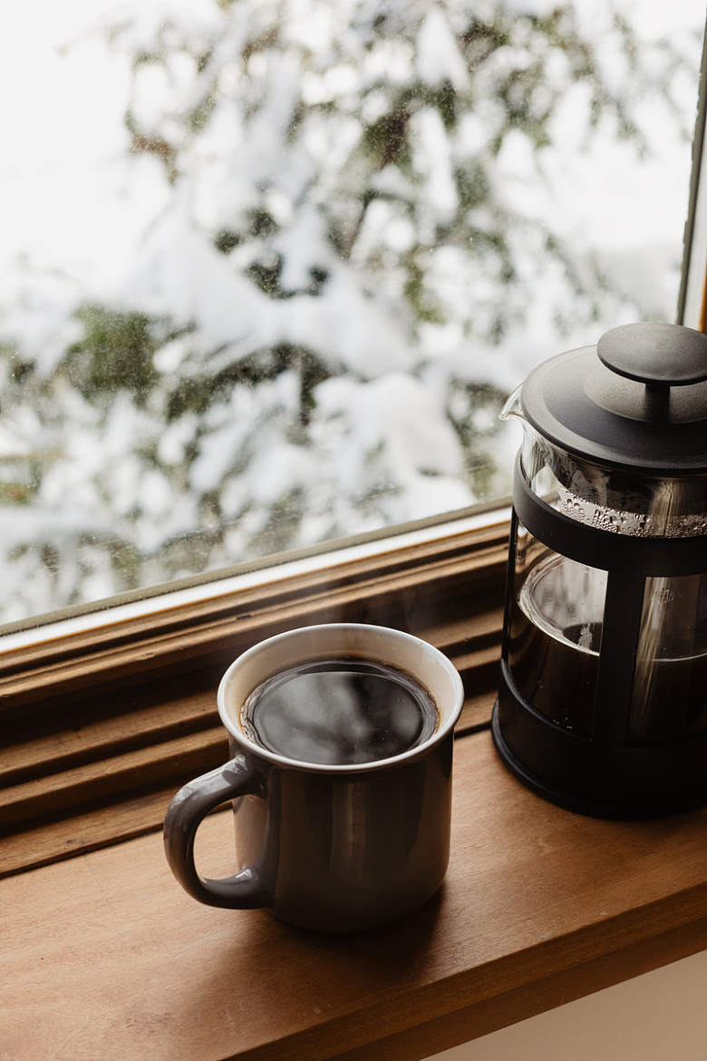 窗台上的一杯咖啡和一台法式压榨机