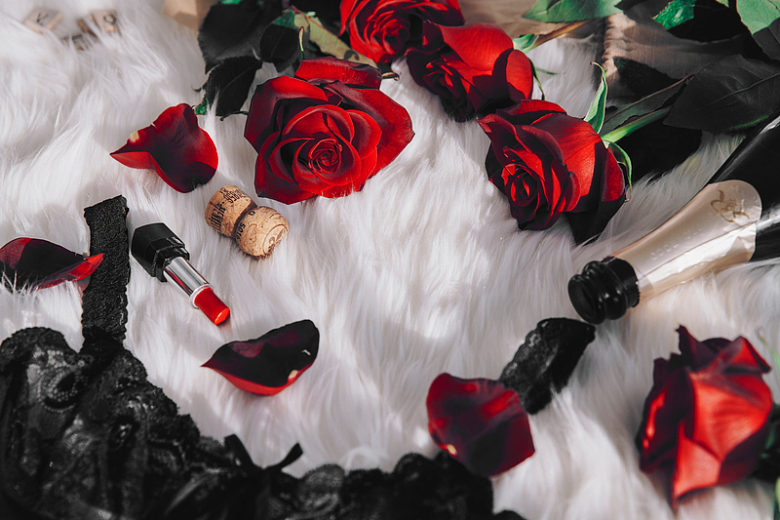 白色毯子上的红玫瑰和红酒