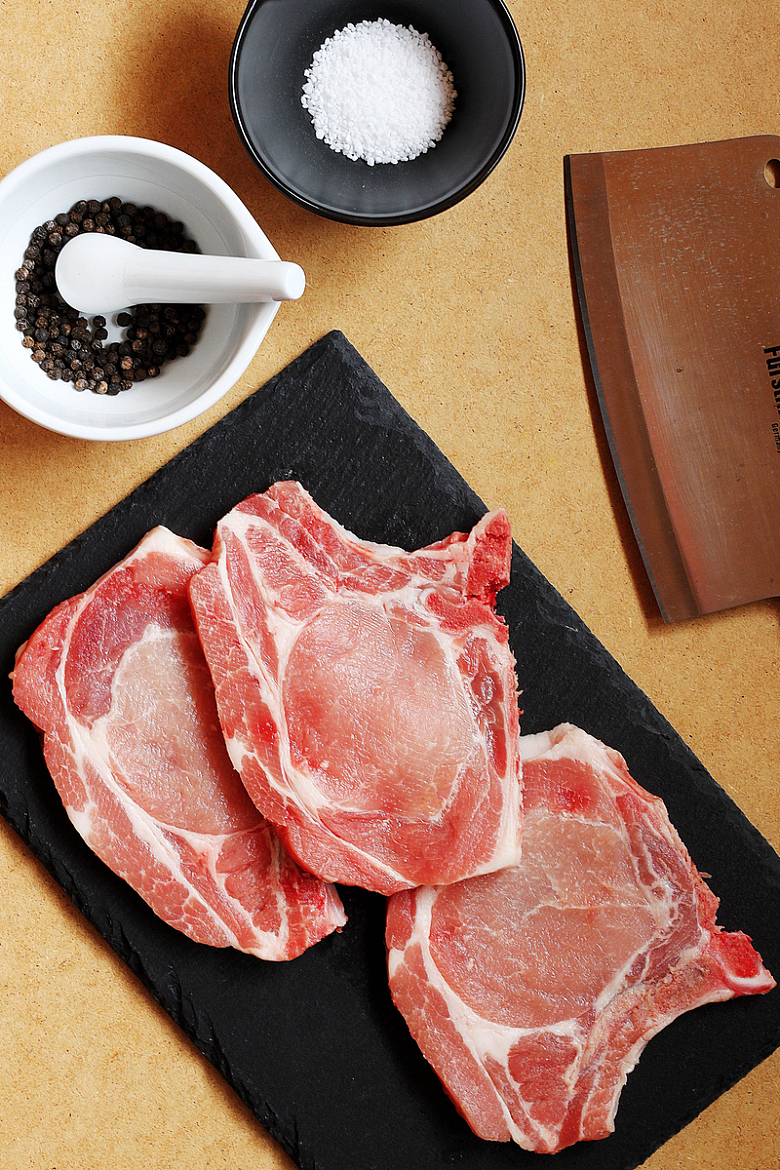 用石板和切肉刀准备和调味生猪排