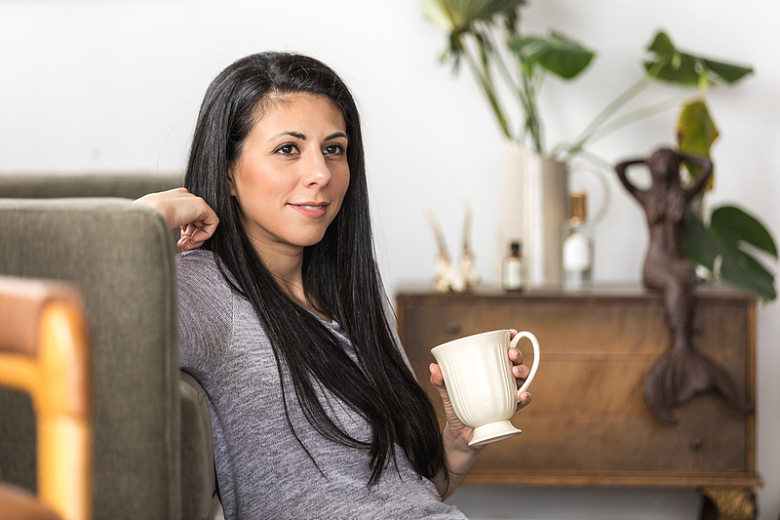 一个年轻女人靠在沙发上喝咖啡