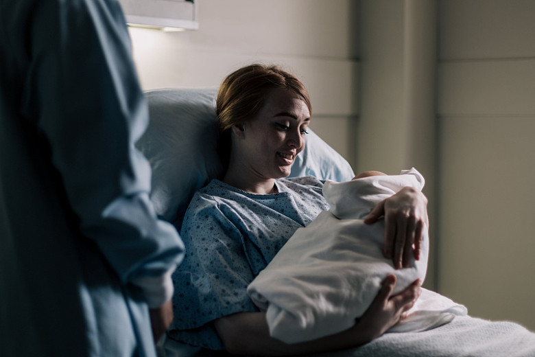 产妇在病床上微笑看着婴儿