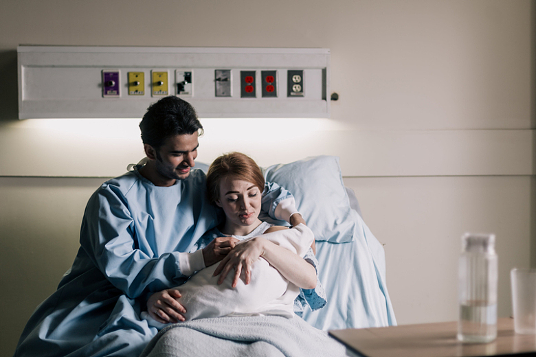 坐在病床上欣赏新生儿的父母