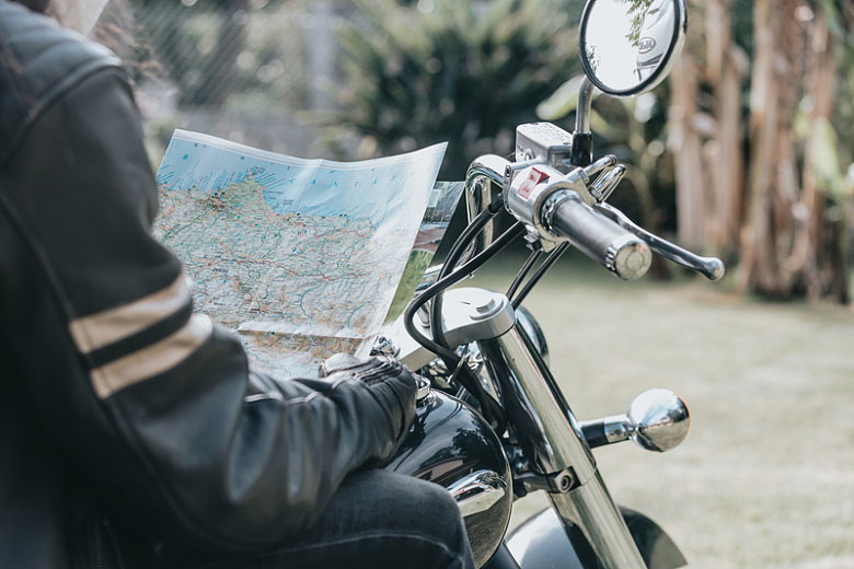 骑在摩托车上拿着地图的人