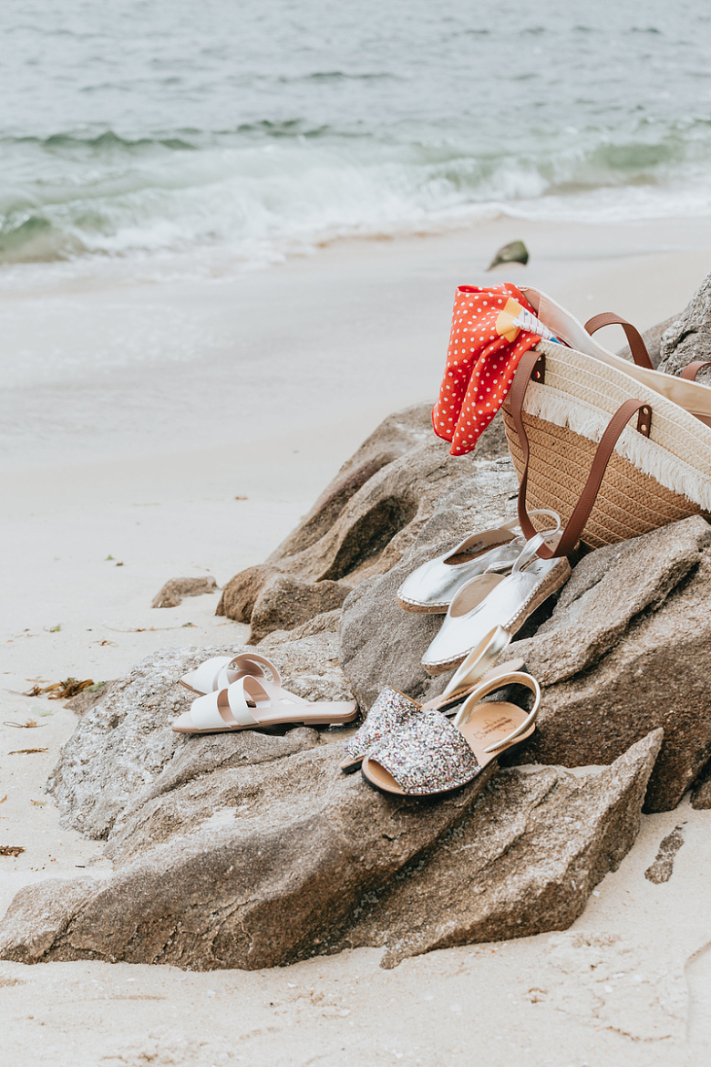 沙滩上的三双夏鞋和一个沙滩包