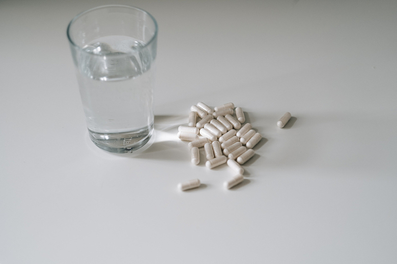 白色台面上的一杯水和药片