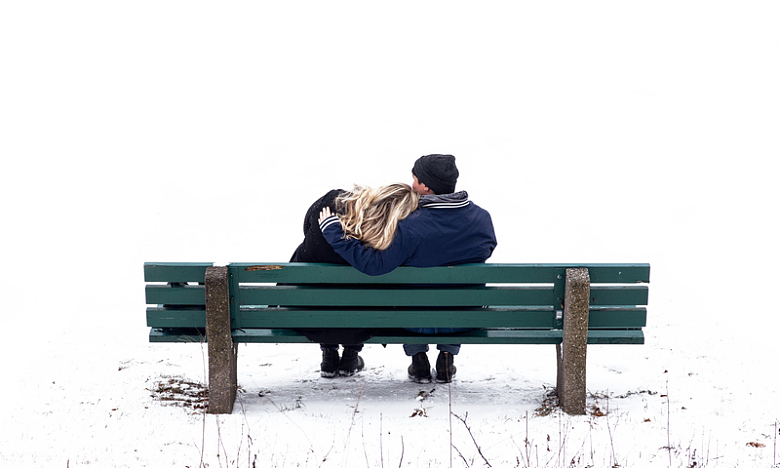 一对情侣在雪地里的长椅上拥抱