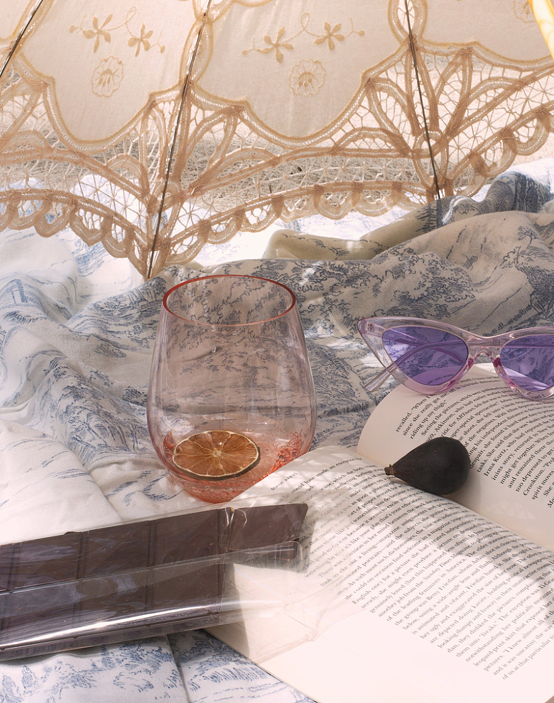 下午茶太阳伞下餐布上的柠檬水巧克力西梅书籍 太阳镜