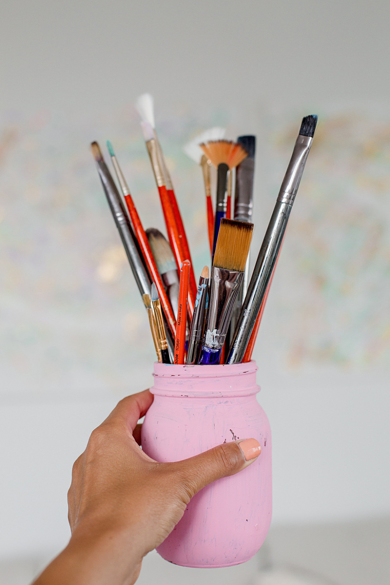 手里拿着一个装满画笔的粉红色笔筒