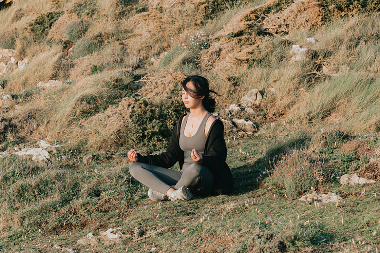 一位妇女在绿色的草山上冥想