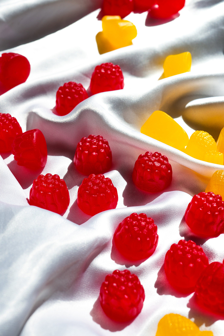 白丝绸上的红浆果形状的糖果