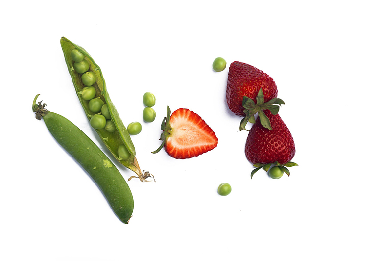 豆荚里散落着绿豌豆和草莓