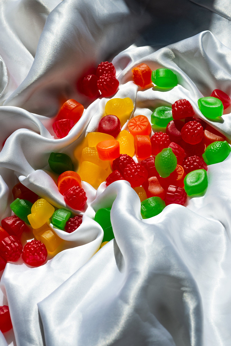 白色丝绸床单上散落着五颜六色的糖果
