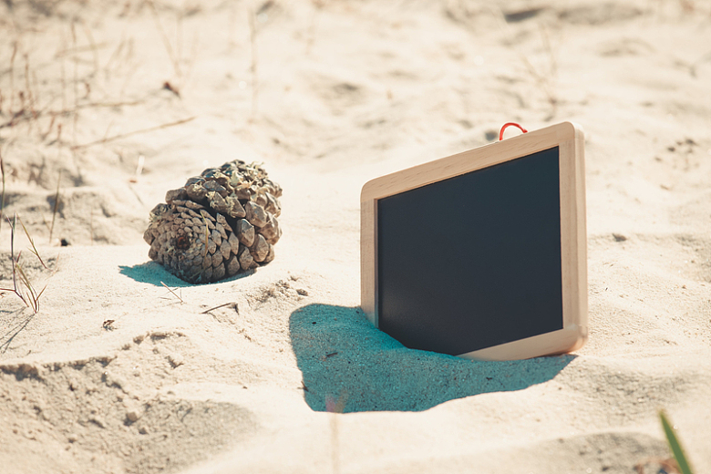 海滩上的沙子上伸出一块空白的黑板