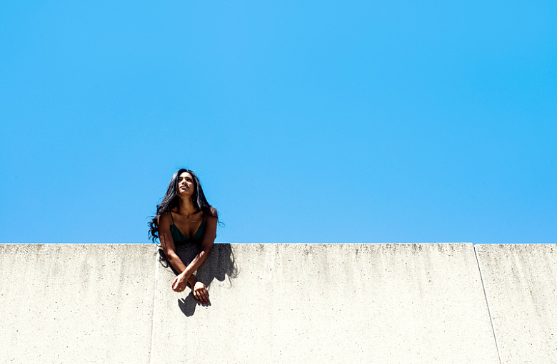 女子倚在蓝天下的城墙上