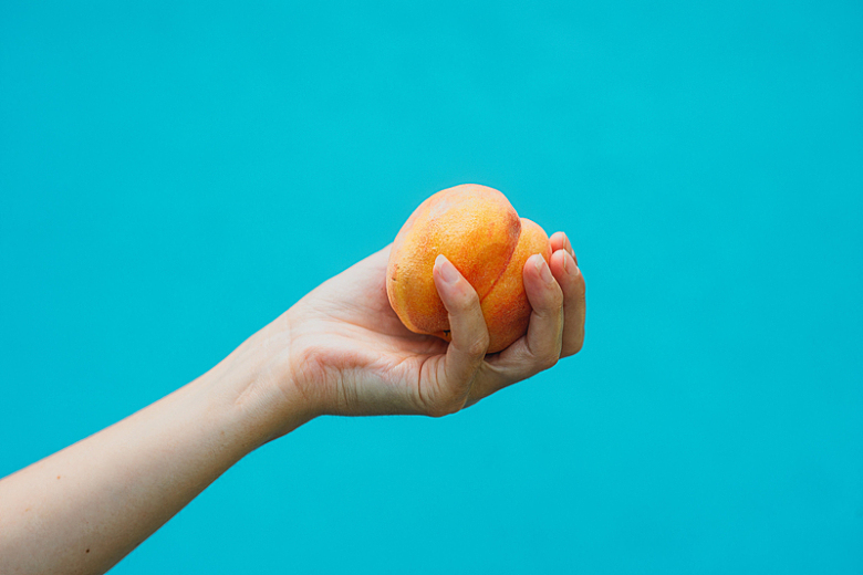 一只手拿着一个成熟的桃子