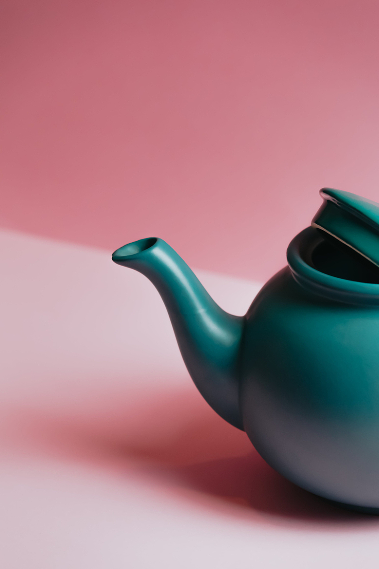 浅粉色背景下的绿色茶壶