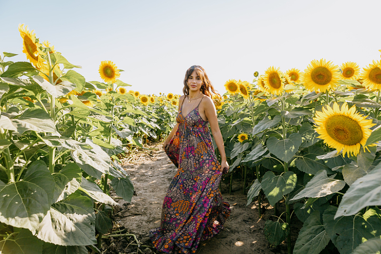 一个穿着碎花连衣裙的女人站在向日葵地里
