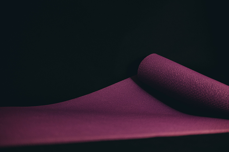 紫色瑜伽垫在黑色地板上展开