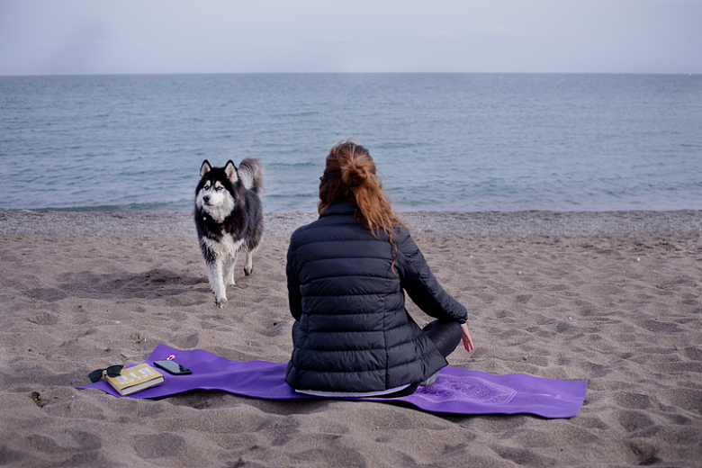 一个人坐在海滩上的垫子上看着外面的水