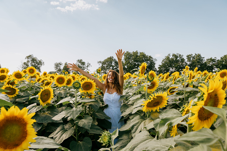穿着白色太阳裙的女人站在向日葵中间