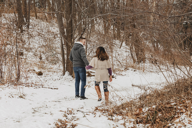 漫步在冬季积雪覆盖森林里的情侣