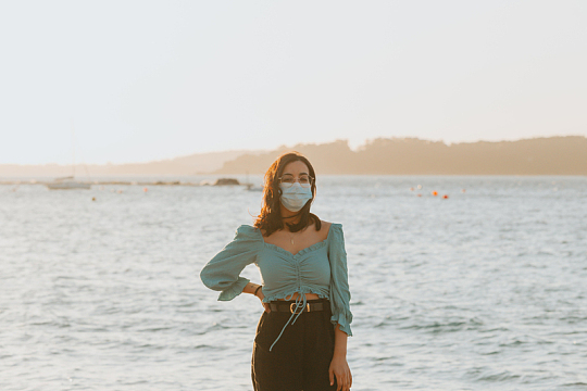 戴着口罩的女人站在湖面前